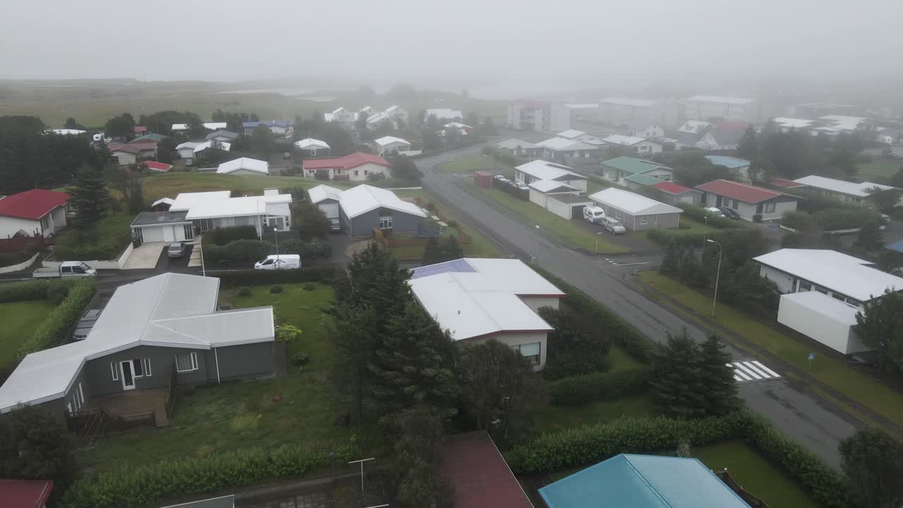 Hover over H&ouml;fn's quaint neighborhood shrouded in fog with our drone's eye view, revealing the town's serene atmosphere in high-definition 4K