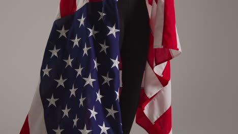 close up studio shot of woman wrapped in american flag celebrating 4th july independence day