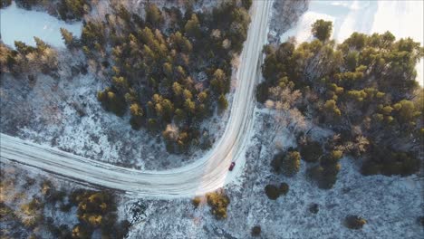 Aerial-Shot-Of-A-Car-Parked-On-A-Road-In-A-Winter-Forest-Landscape