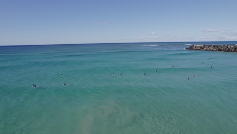 Playa-Duranbah-Con-Surfistas-Flotando-En-El-Agua-En-Nsw,-Australia---Retroceso-Aéreo