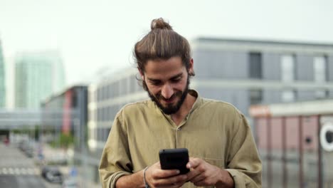 hombre sonriente enviando mensajes de texto por teléfono inteligente