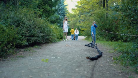 Little-boy-is-dragging-a-branch-along-the-forest-road