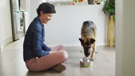 caucasian woman feeding her dog in the living room at home