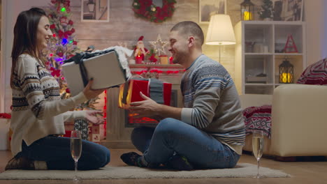 cheerful couple giving each other gifts on christmas day