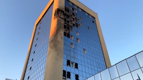 los cohetes bombardearon y destruyeron un alto rascacielos con ventanas de vidrio rotas en la calle solomianska en kiev, ucrania, daños críticos de guerra en la capital de la ciudad, rusia ataca ucrania, 4k inclinándose hacia abajo