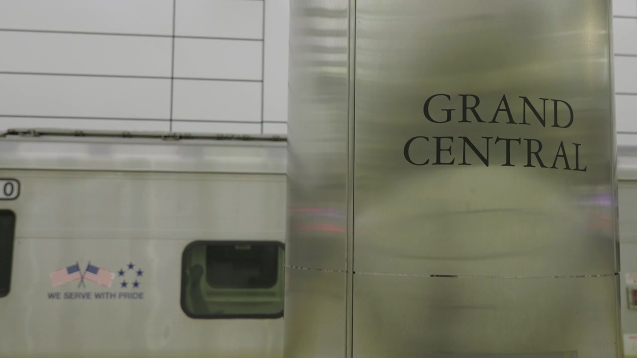 Nærbilde av søyle på Grand Central Station med et tog fra Long Island Rail Road (LIRR) i bakgrunnen.