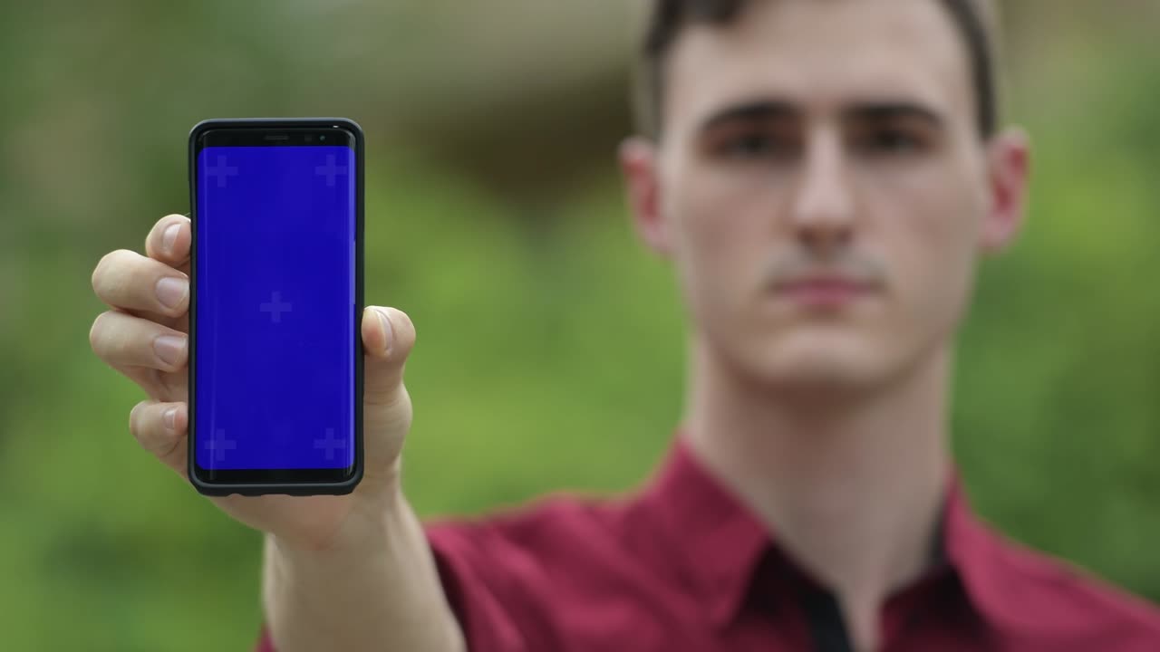 joven hombre de negocios guapo mostrando el teléfono en las calles al aire libre