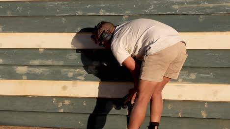 man fixing wooden beach box at brighton beach