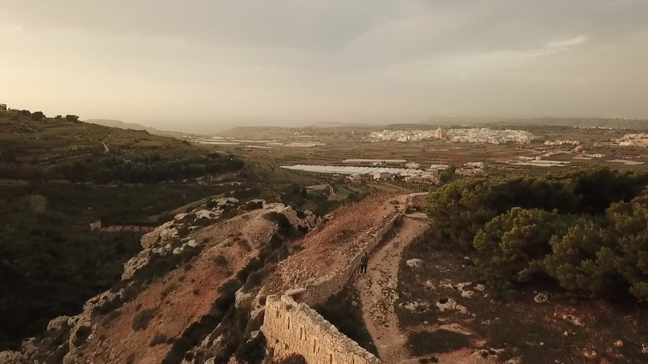Aerial view of the Victoria Lines, Malta, Europe. Flying over the wall with a tourist walking on the wall.