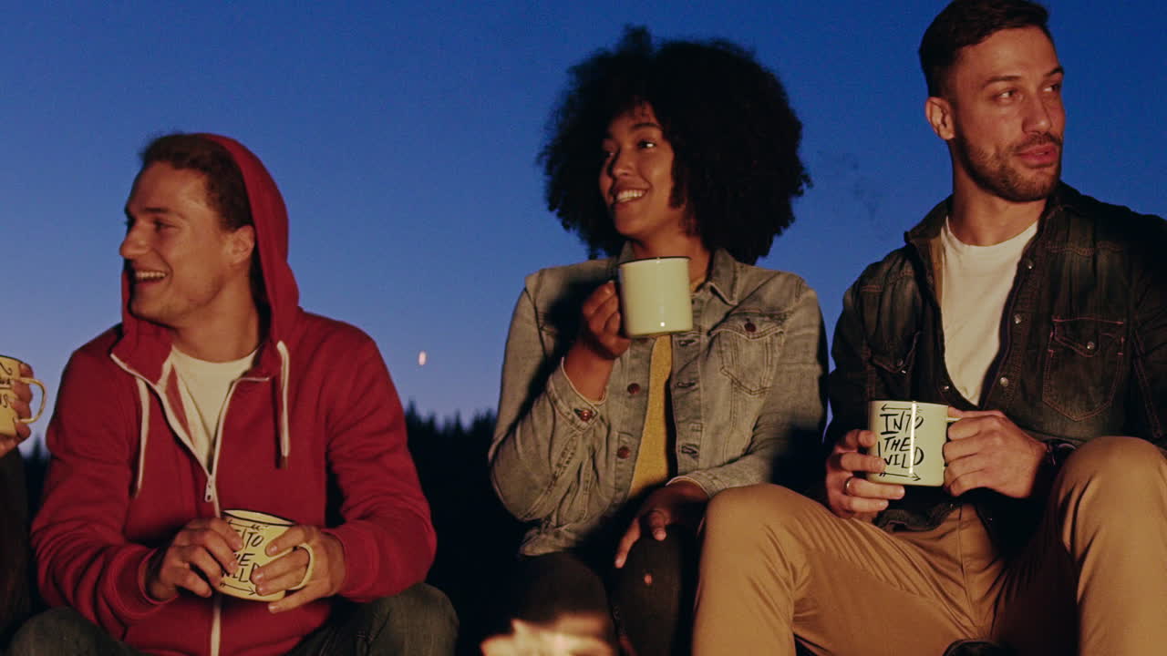 친구들이 캠프 불 에서 술을 즐기고 있습니다.