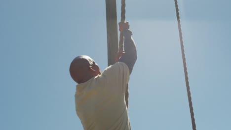 Fit-african-american-male-soldier-climbing-rope-on-army-obstacle-course