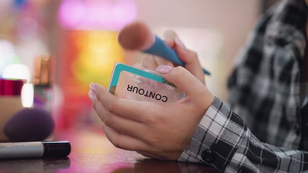 vista de cerca de las manos de la mujer abriendo el estuche de polvo de contorno y aplicando delicadamente el maquillaje con un pincel suave, rutina de belleza en progreso, mostrando precisión, cuidado de la piel y elegancia en el cuidado personal