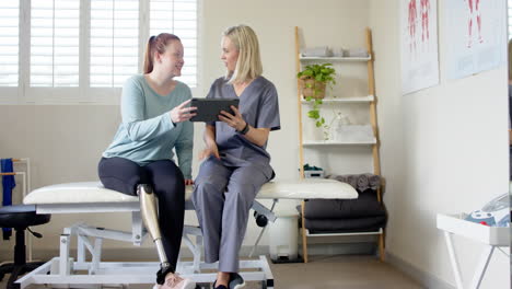 woman with prosthetic leg discussing treatment plan with therapist using tablet, copy space