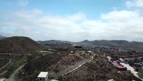 drone footage of haciendo las delicias, baja, mexico in the daytime. starts up close then cinematically reveals more hillside homes and mountains.