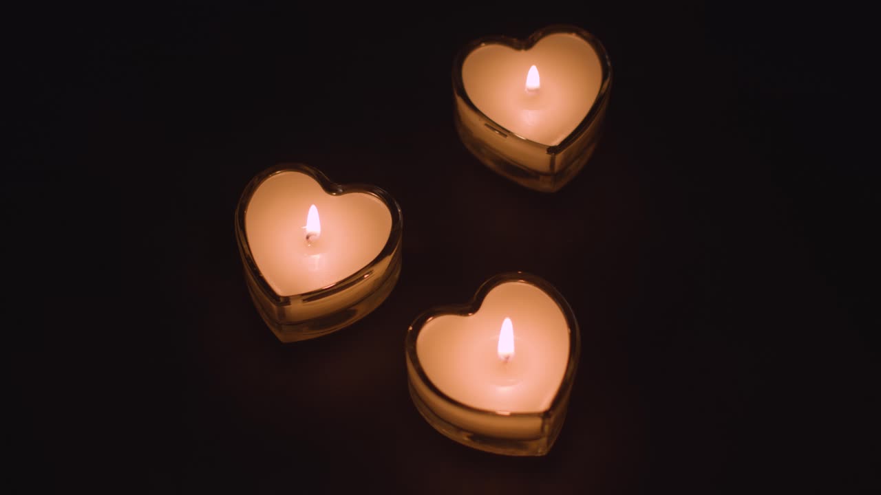 Close Up Of Three Romantic Lit Heart Shaped White Candles On Black Background With Copy Space 1