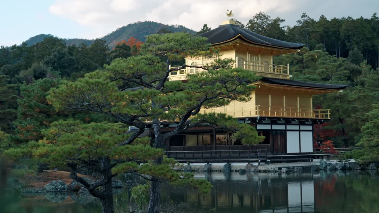 The stunning Golden Pavilion, Kinkaku-ji, reflects beautifully on the calm pond, surrounded by vibrant autumn foliage in Kyoto, Japan.