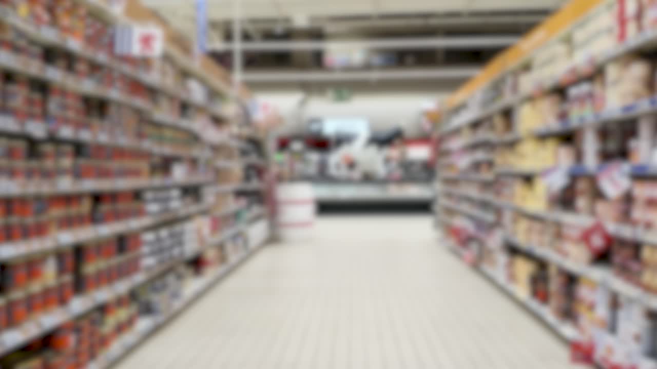 A smooth out-of-focus camera movement travels down a brightly lit retail grocery store aisle