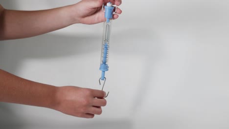 hand demonstrating a blue spring scale