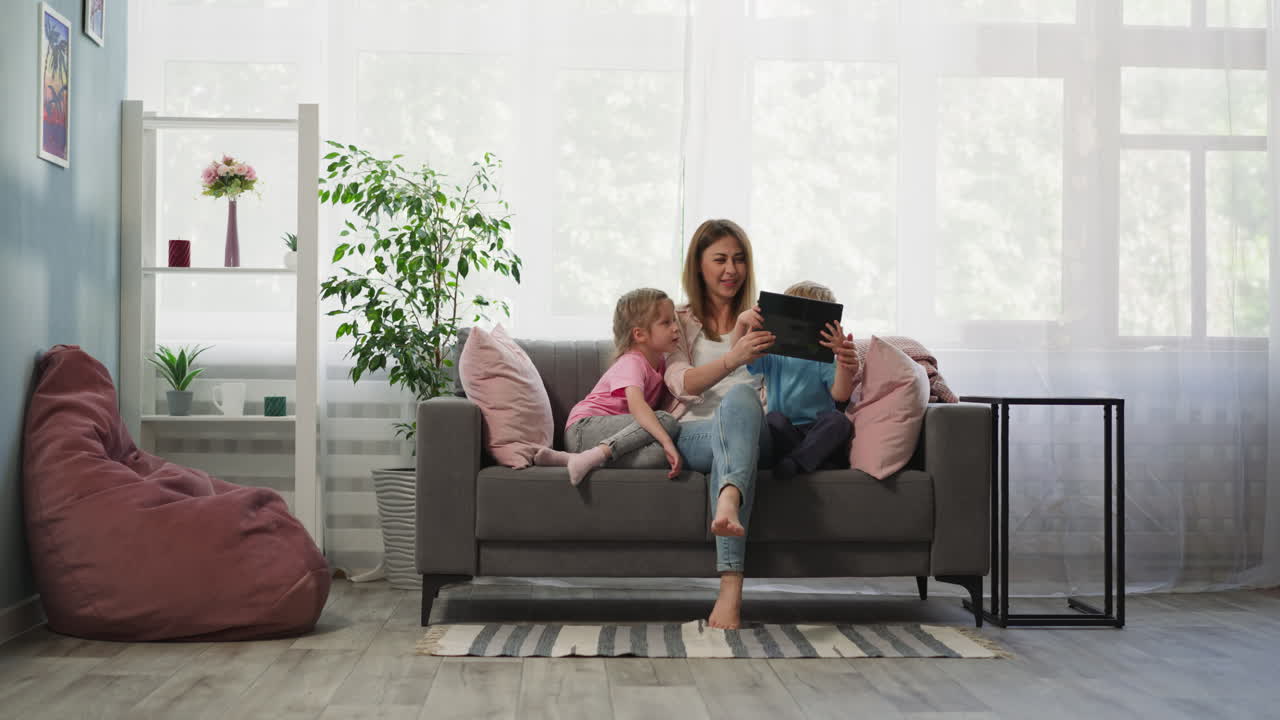 la madre muestra a los niños curiosos dibujos animados interesantes en la tableta