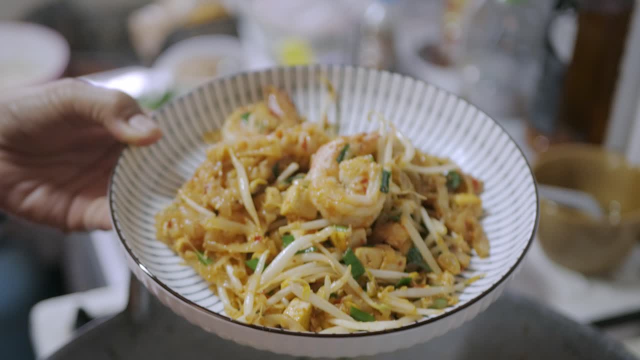 Legger Pad Thai fra pannen over på tallerken, klar til å spises
