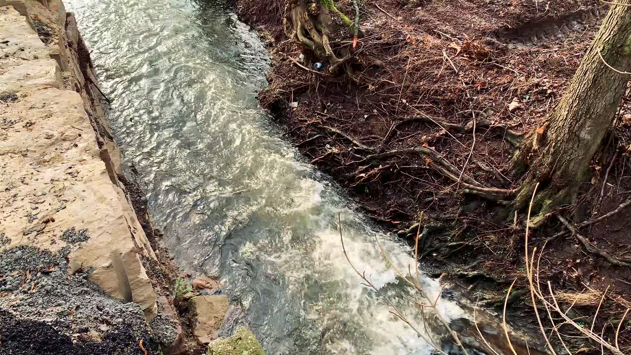 Fiume impetuoso lungo un muro di pietra