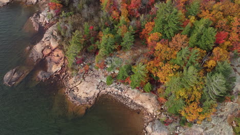 drone revealing the crystal clear water of the bay around the rocky shore at killbear provincial park in fall season