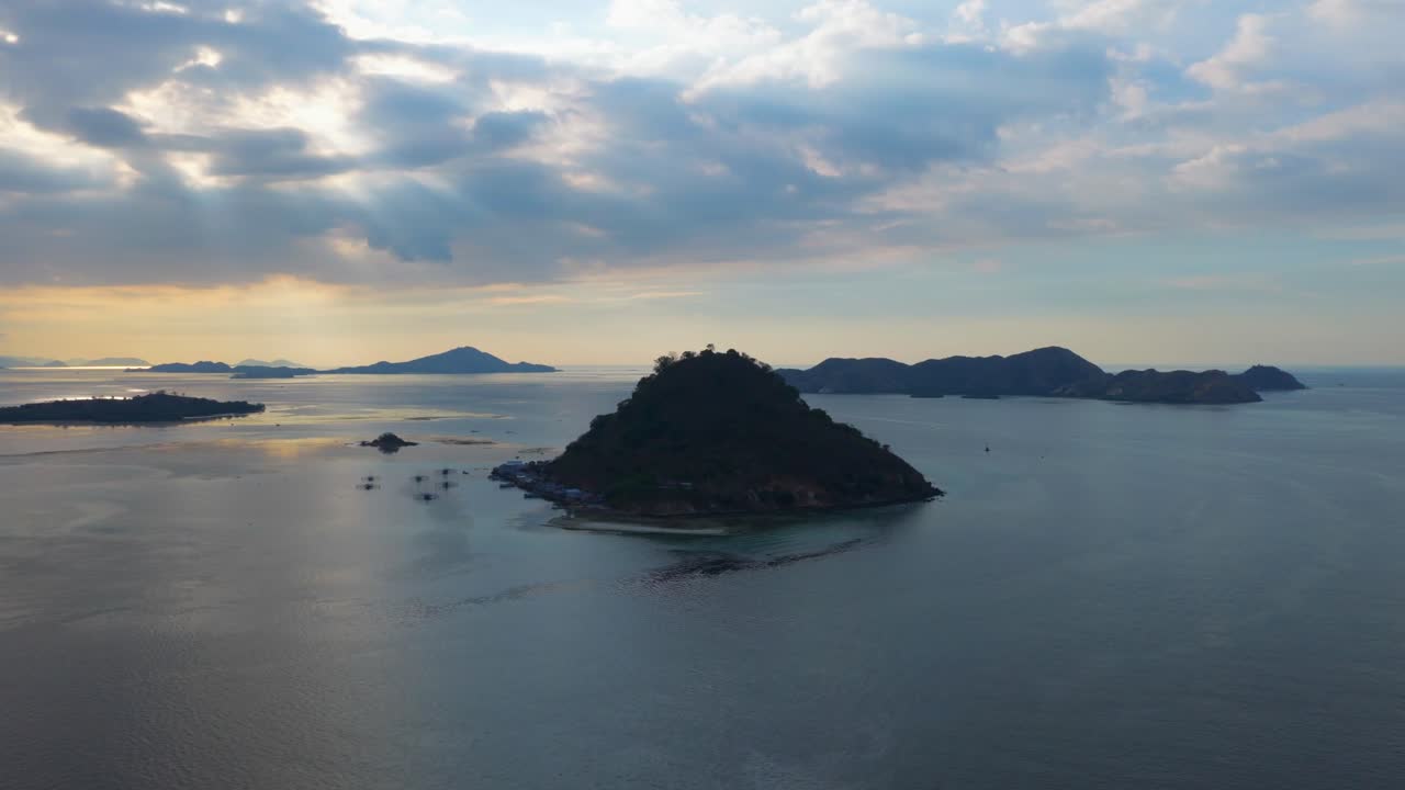 Aerial view of a hilly island surrounded by calm sea with distant islands on the horizon