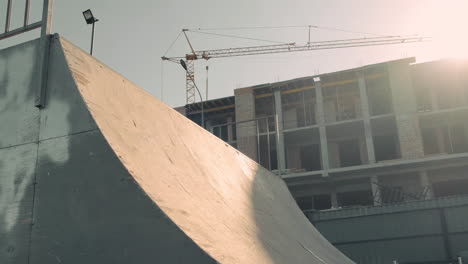 joven patinadora haciendo trucos en una rampa en un parque de patinaje frente a una casa en construcción