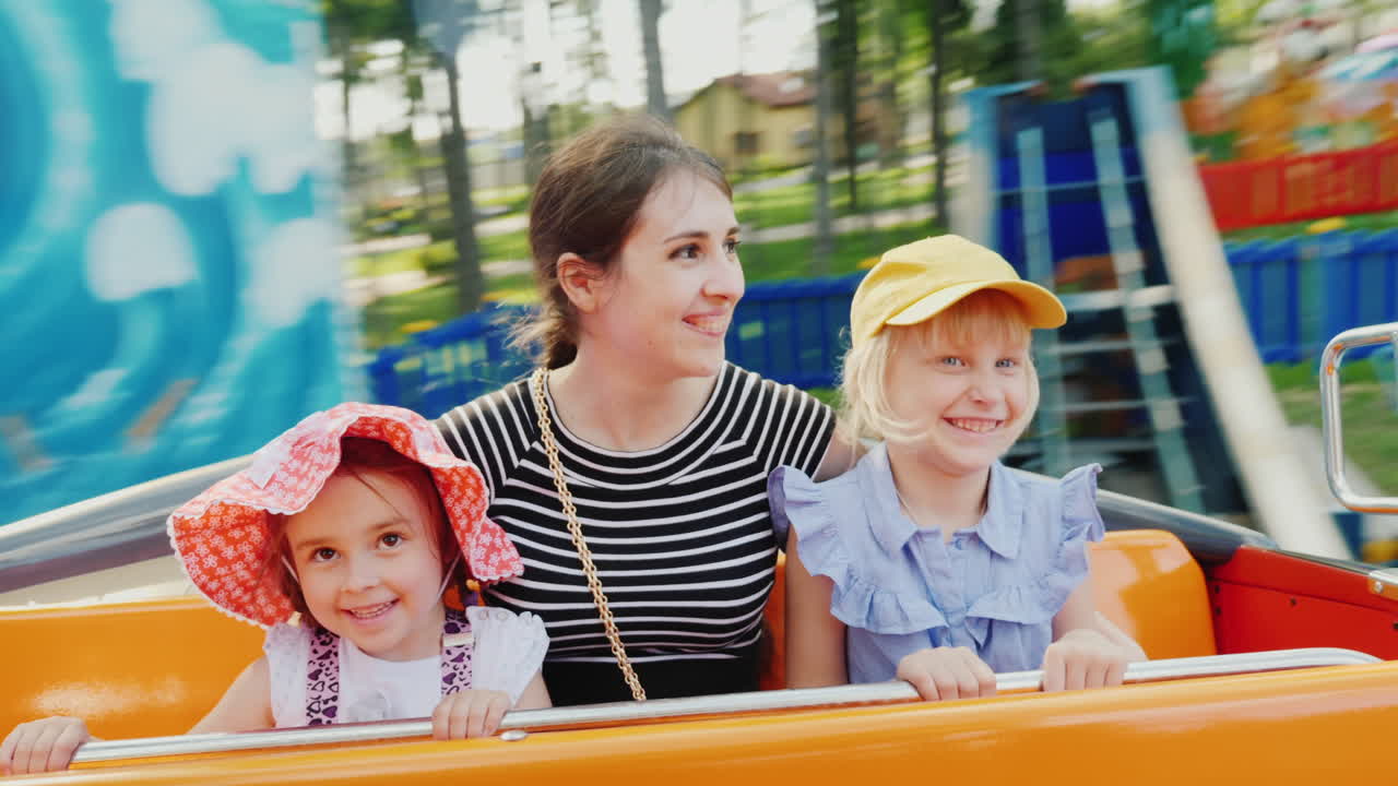 공원에서 그네를 타고 두 딸과 함께 행복한 젊은 어머니