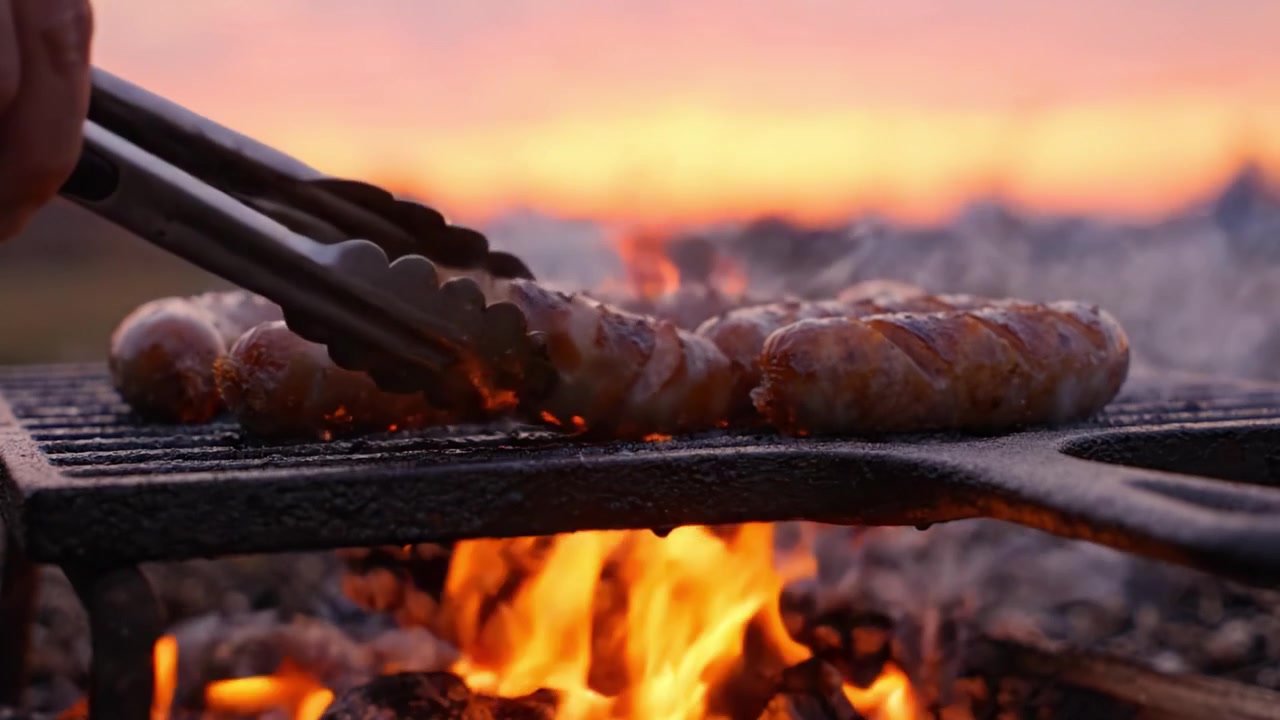 Salsichas Grelhadas sobre Chamas ao Pôr do Sol, Capturando a Vibe Perfeita de Churrasco com Sabores Deliciosos e Fumaça Aromática Subindo no Céu Quente do Entardecer