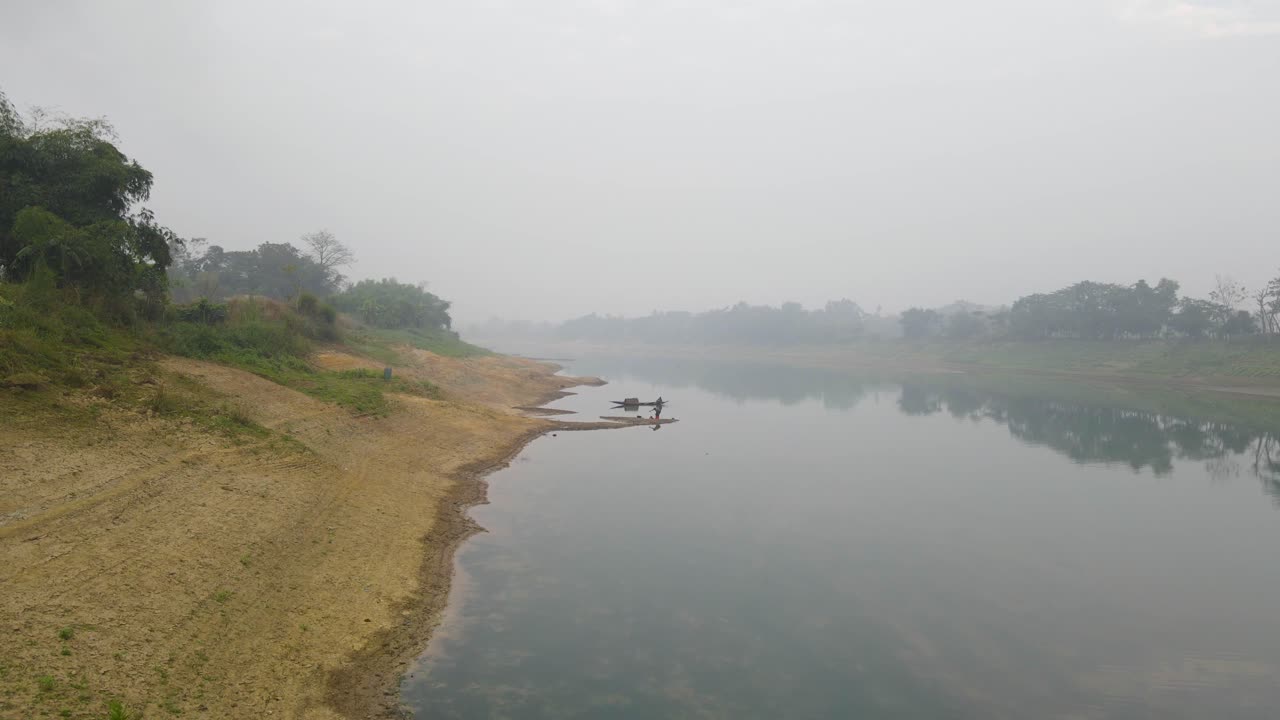 un dron que asciende por encima de la orilla del río surma para revelar un pequeño barco de pesca atado a un poste