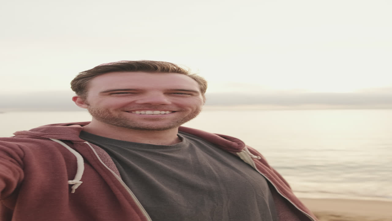 Homem sorri em uma selfie na praia