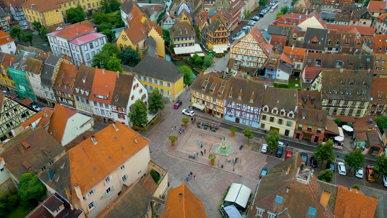 4K-Drohnenvideo von Touristen, die zwischen Fachwerkhäusern und historischen Gebäuden entlang des Flusses Lauch im Viertel Klein-Venedig von Colmar, Frankreich, spazieren.