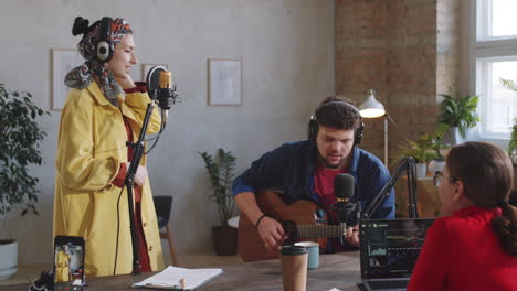 music duo singing in recording studio as podcast host giving applause