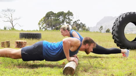 hombre y mujer en forma haciendo flexiones durante una carrera de obstáculos