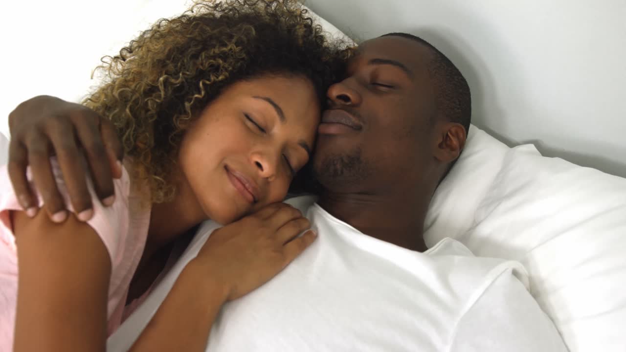Young couple sleeping together on bed