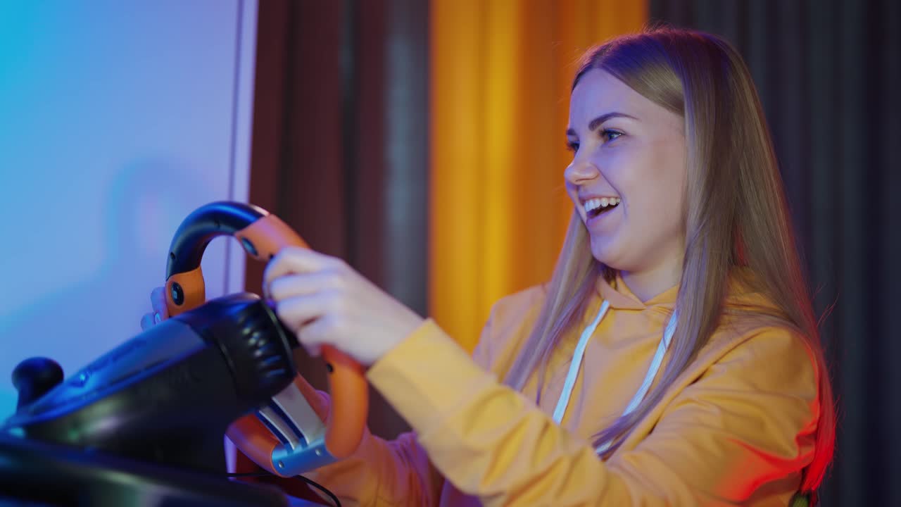 Portrait of a girl enjoying game on a computer. Smiling young woman playing video games using a racing steering wheel. Entertainment concept.