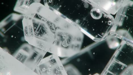 close-up of crystal-like structures in liquid, showcasing their intricate details and bubbles as light reflects, creating a mesmerizing visual experience