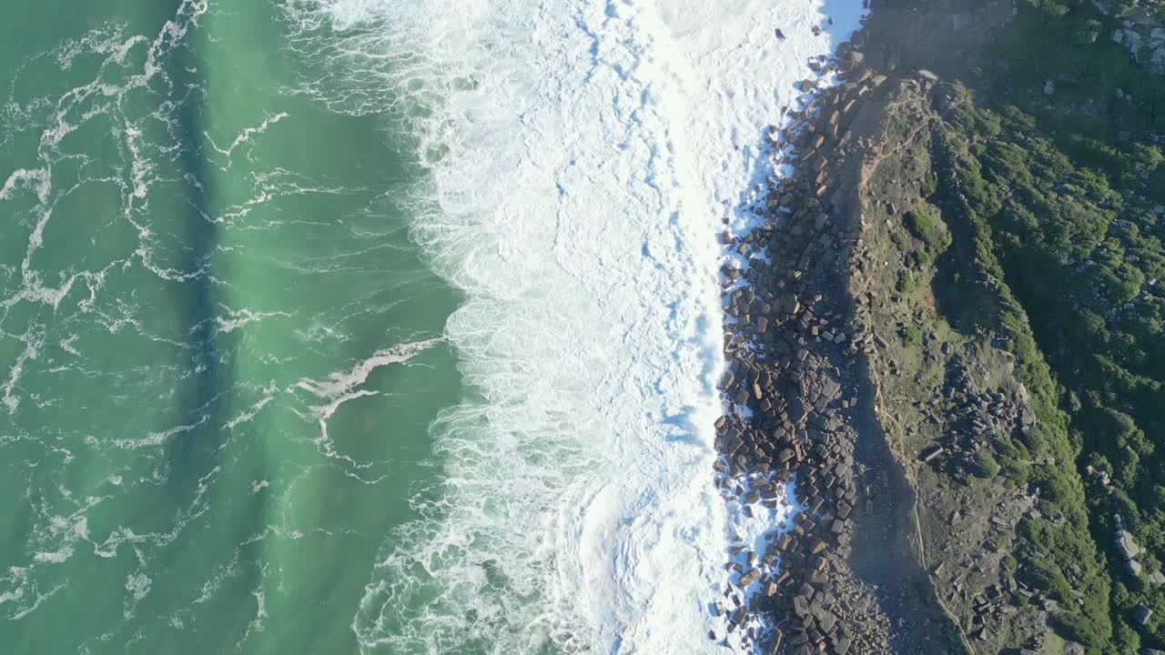 Strong ocean waves crashing on rocky coast in nazaré, portugal, aerial view