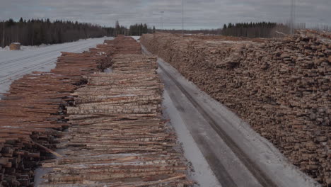 Cinematic-aerial-tracking-shot-over-stacked-timber-in-the-snow