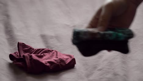 men use their hands to fold men's underwear to keep it organized and easy to store and use