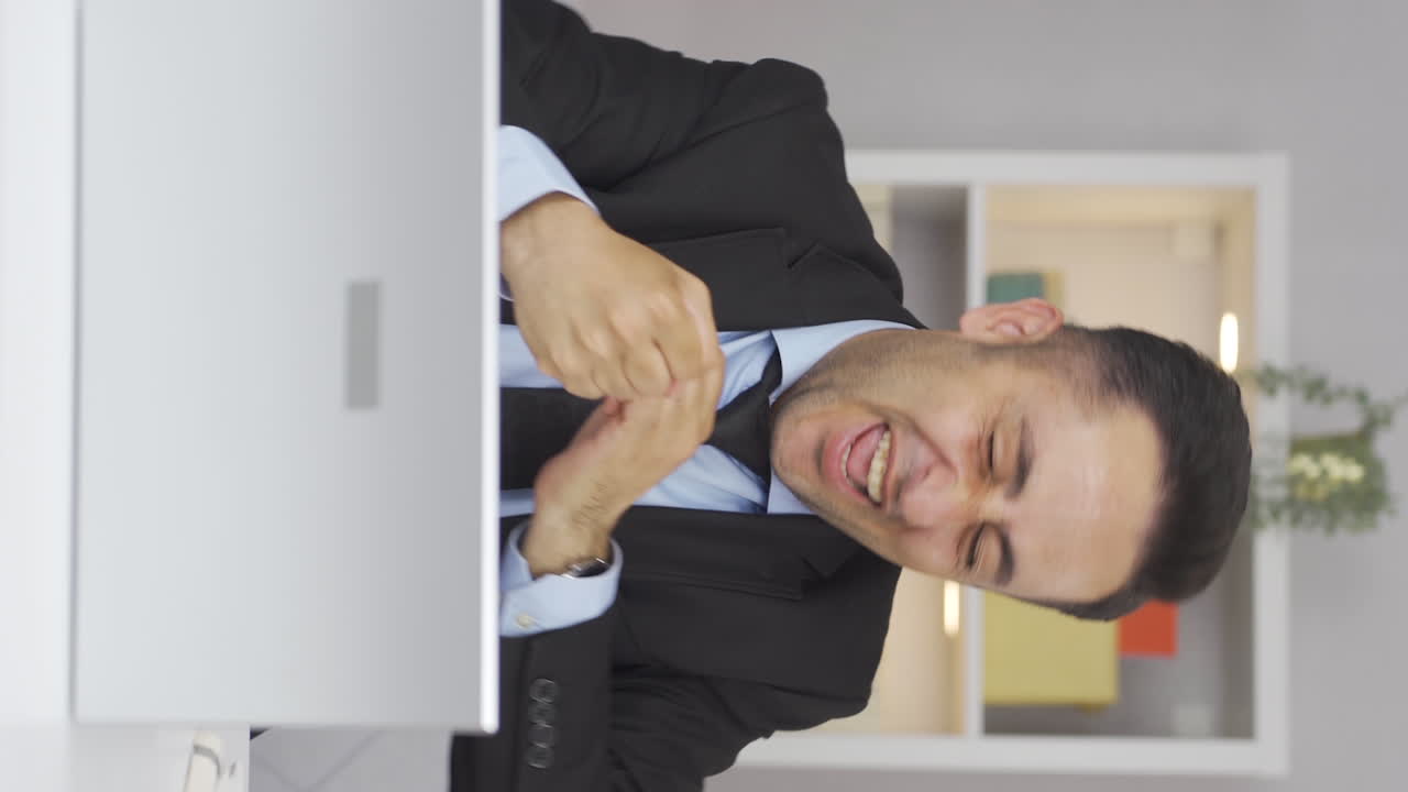 Vertical video of Home office worker man experiencing joy looking at camera.