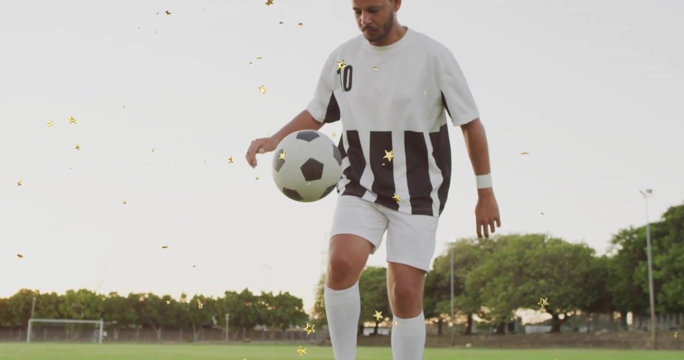 Encuadre de ángulo bajo de las piernas de un jugador de fútbol masculino haciendo malabares con el balón en el campo durante un entrenamiento deportivo.