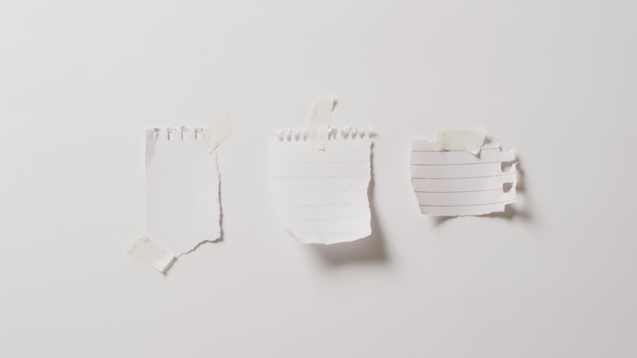 Video of close up of three scraps of paper with copy space taped on white background