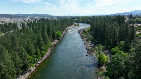 wide aerial view of the spokane river surrounded by trees with the spokane valley off in the distance