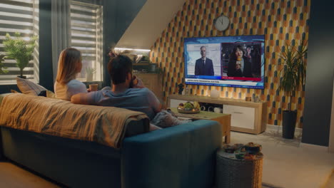 couple watching news on tv at home