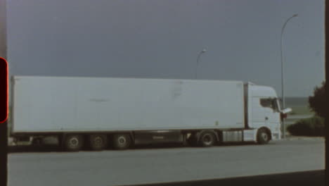 filmed on super 8 film vintage, retro looking footage of a white articulated lorry on a coastal road