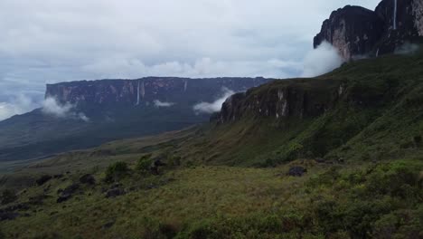 avión no tripulado volando sobre la hierba en la base de roraima tepuy con cascadas y nubes que lo cubren