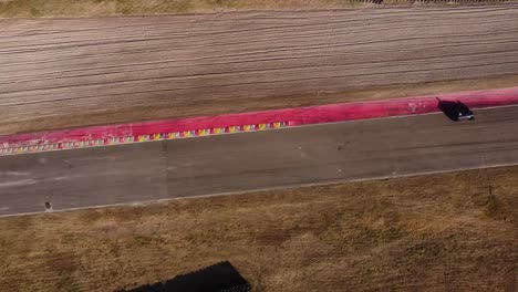 aerial flyover racetrack and old vintage race car passing by during sunlight