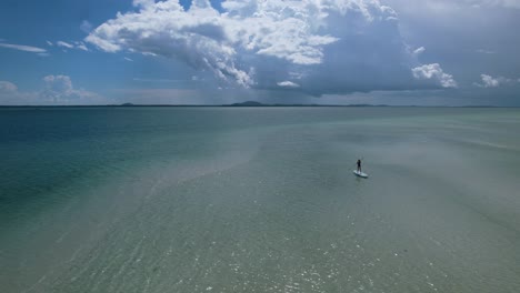 persona haciendo paddle surf en un océano tropical cristalino